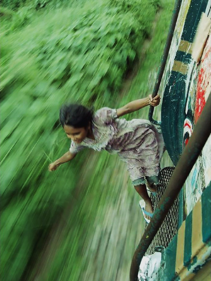 truangles:A Bangladeshi girl hangs on to the side of a train, taken by Tab Tuhin