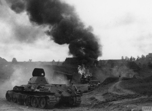 A knocked-out Soviet T-34 medium tank and other burning vehicles on aroad somewhere between Białysto