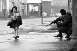 salahmah:  Young Girl strolls past a British Soldier, with her groceries. Belfast, Ireland, 1969.