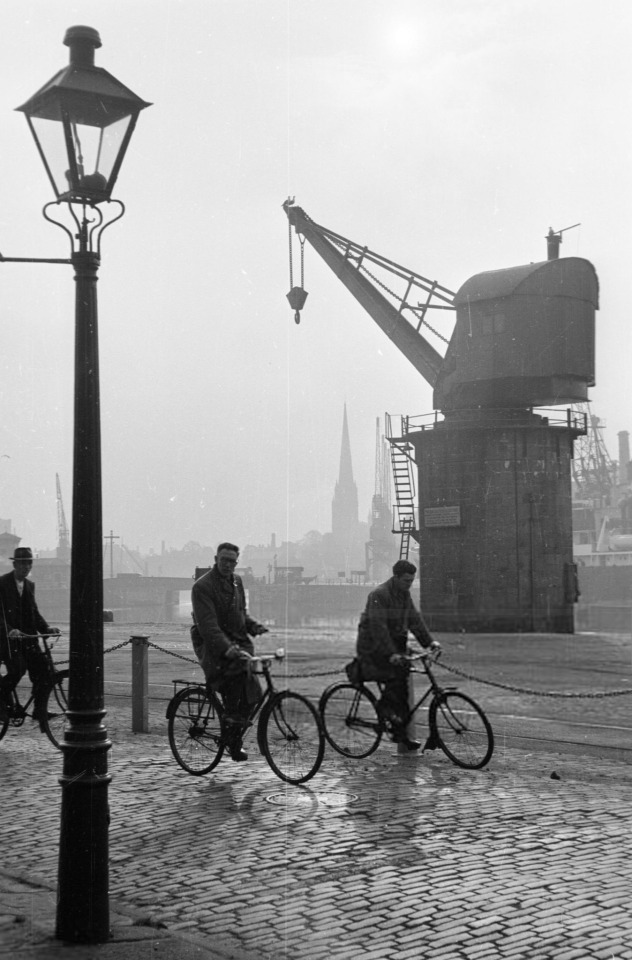 Joseph McKeown. Cyclists riding bikes near the old dock area of Bristol. 1954