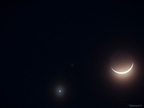 The moon, Venus, and Mars, seen through a thin layer of cloud.Venus and Mars are in line with each o