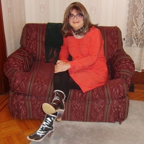 Full-length picture of me, seated, legs crossed, knees right, wearing my new purple cat-eye glasses,