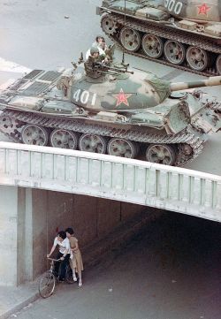 historicaltimes: Couple on a bicycle take cover beneath an underpass as tanks deploy overhead during the Tiananmen Square protests, June 5, 1989 via reddit 