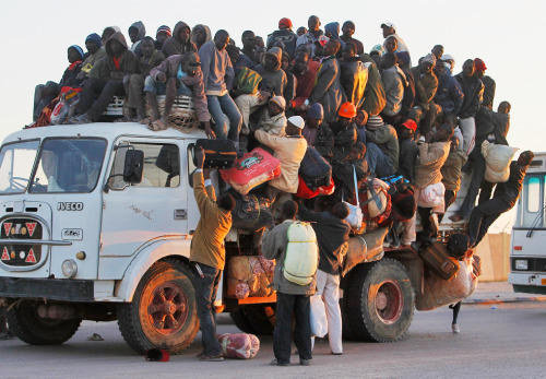 Foreign workers from Nigeria, Ghana, and other African countries pile in the back of a truck with th