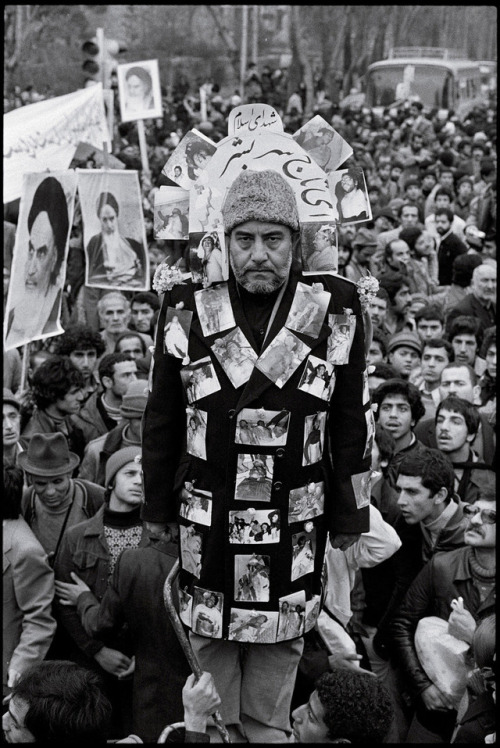 historium:A supporter of the Iranian Revolution attends a rally in Tehran covered in photos of peopl