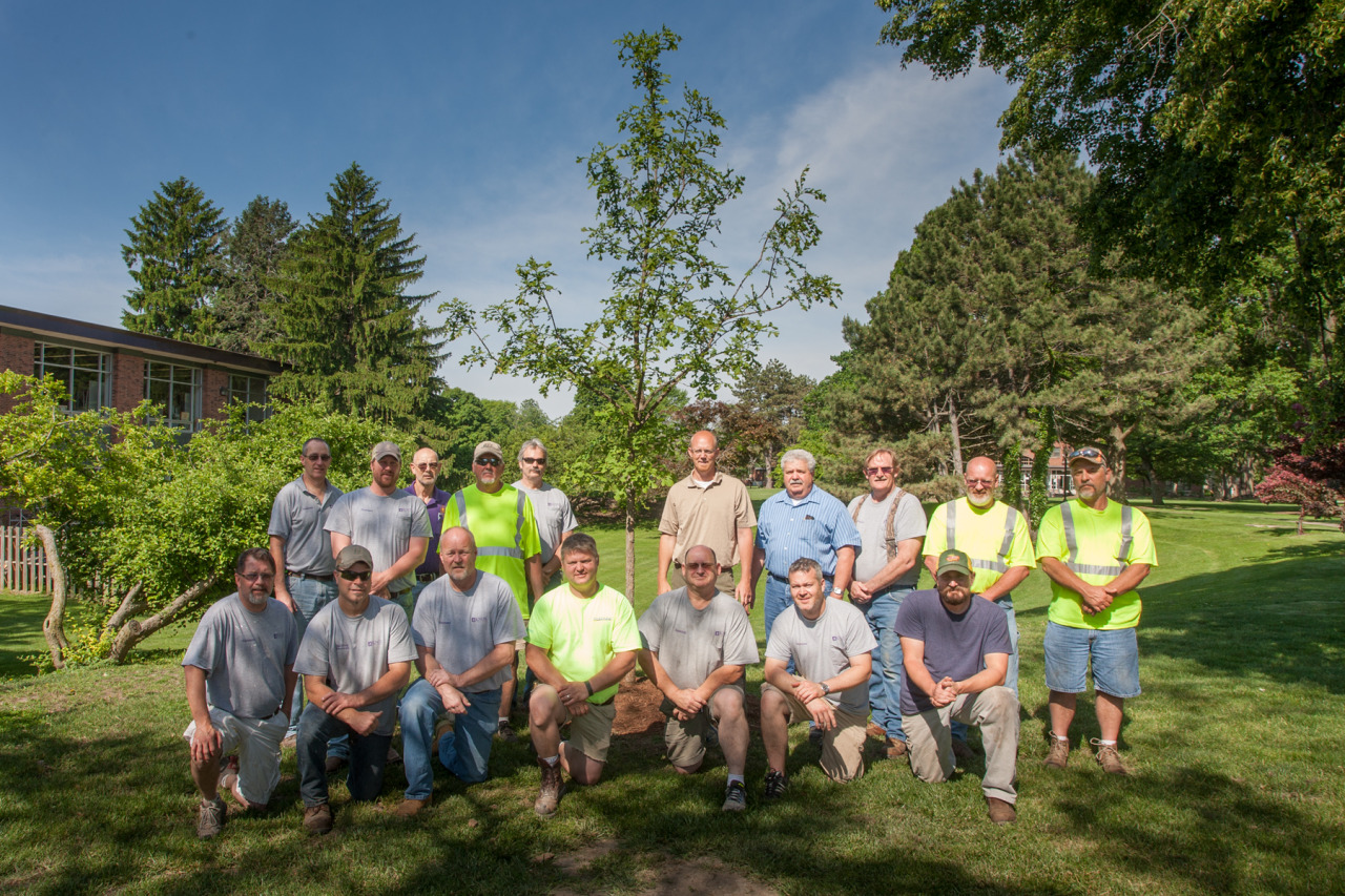 Knox College facilities services staff gather at a tree donated in memory of Andy Pitman.