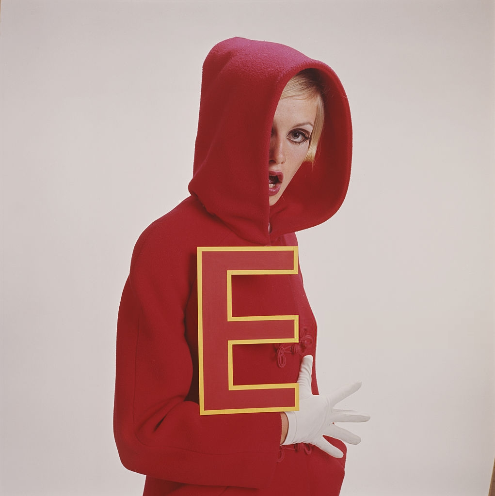 ohyeahpop:Twiggy in a red hooded jacket and white gloves whilst holding a large red