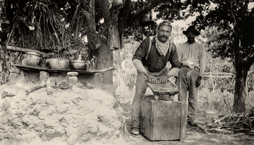 Workers grind corn on a metate to make tortillas, Mexico