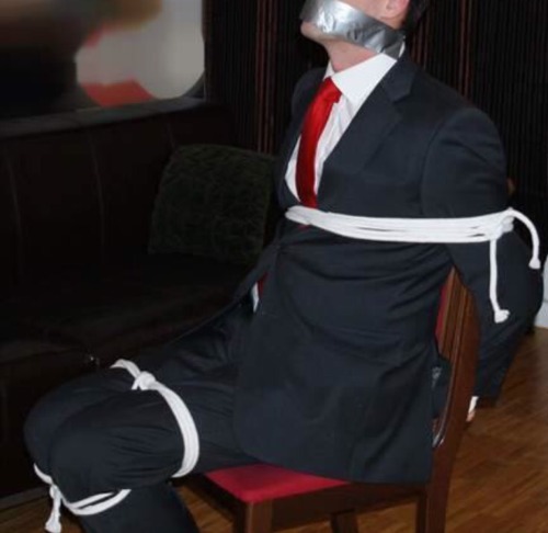 rennegade15:  tied up Businessman in a dark grey suit + white shirt + red tie + white ropes 