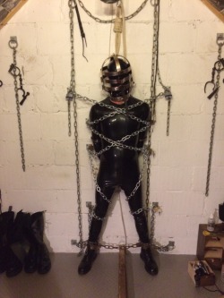 jamesbondagesx:  Rubber boy cuffed chained and in head cage secured to the wall with padlocks 