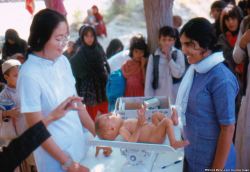 visitafghanistan:  A child being measured and weighed in a village clinic. The woman on  the left is an American Peace Corps nurse working with an Afghan student  nurse (right).