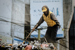 A garbage man working on top of a pile of