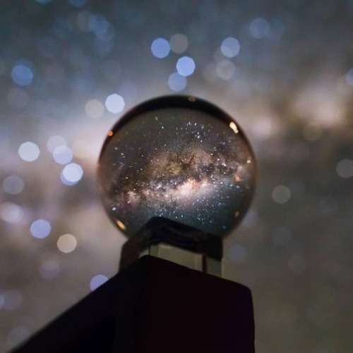 Galaxy in a Crystal Ball   Image Credit & Copyright: Juan Carlos Munoz  Explanation: A small crystal ball seems to hold a whole galaxy in this creative snapshot. Of course, the galaxy is our own Milky Way. Its luminous central bulge marked by rifts