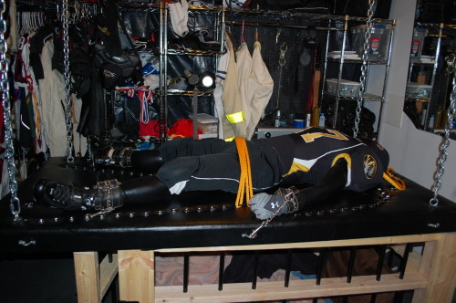 gearjockmo:  Restraining down to the training table. Tine for this jockfag to be worked over, rope in the middle is to make sure his cup is pulled down tight over his chastity device. Scene from my playroom. 
