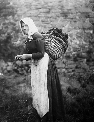 thursen:Woman knitting whilst carrying a kishie of peats. Note needles are very short and yarn bundl