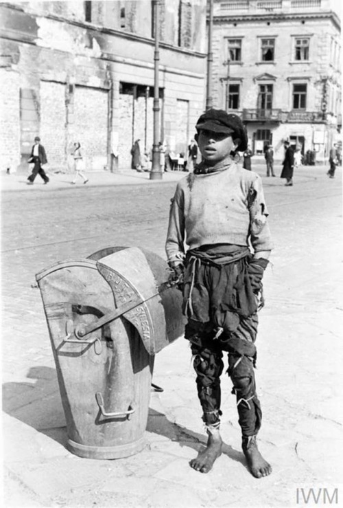 A teenage boy in ragged clothes stands next to a waste containerproduced by Silesia Steelworks in Ry