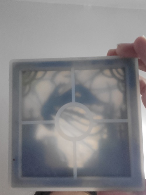 a view through the bottom of the silicone mold. The layers of paper can be seen indistinctly and blurry in shades of gray and black.