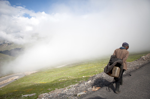 A worker walks along the top of a mountain road on the Leh-Manali Highway Himachal Pradesh, India