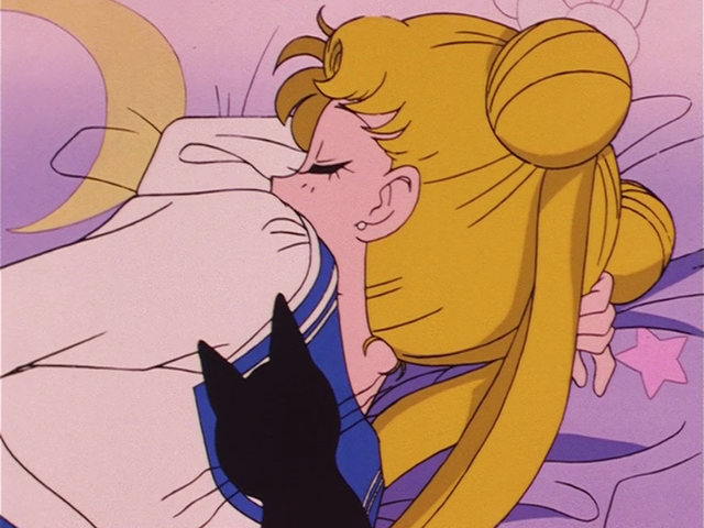 Screencap from Sailor Moon (1992) with Usagi Tsukino, a teenage girl with blonde pigtails and hair buns, snoozing on her purple comforter. The shadow of a cat is silhouetted dramatically on her back.