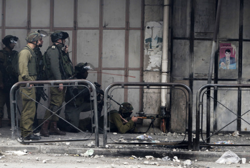 politics-war:Israeli soldiers take position during clashes with stone-throwing Palestinian protester