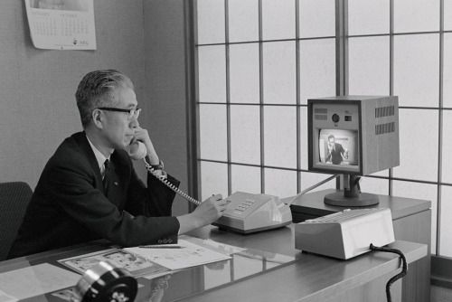 aiiaiiiyo: This Japanese Executive communicates with one of his subordinates via a new video telephone in his office. The multi channel videophone was invented and installed by the Nippon Electric Company and cost ũ,300 U.S. dollars for a one-channel