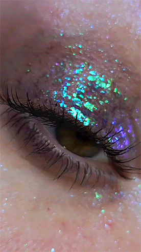 A continuation of the previous gif. The eye, now opened, blinks rapidly. The blinking causes the eyeshadow to quickly shift colors. End ID.