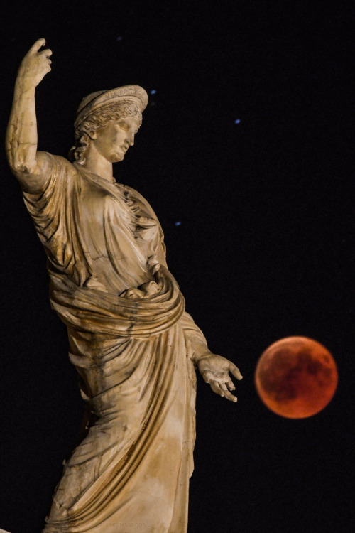 greekromangods: The full moon during a “blood moon” eclipse beside a statue of the ancie