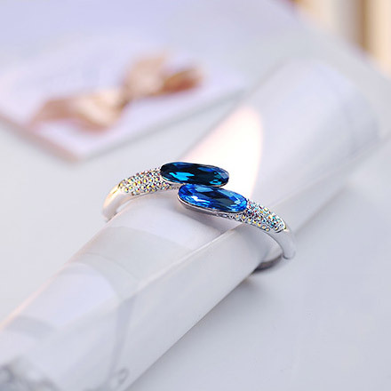 This trendy sterling silver bangle bracelet offers a stunning blue crystal and rainbow beading contr