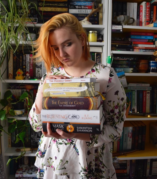me, standing in front of my bokkshelves, holding a stack of books in my hands