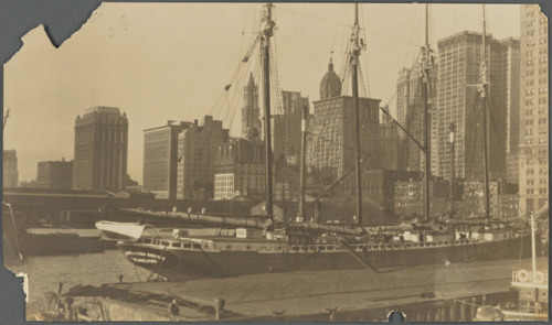 Lower Manhattan and a four-masted schooner on the East River, from the East River piers in either Br