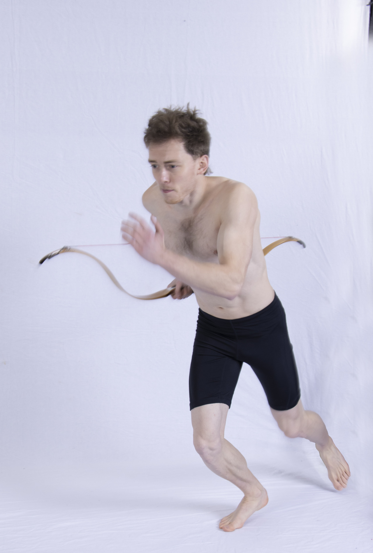 A photograph of a man running while holding a bow
