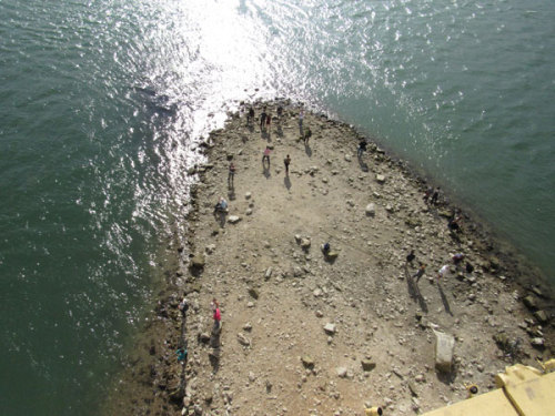 People stand on dry ground, which is an extension of Margaret Island, temporarily exposed by the low