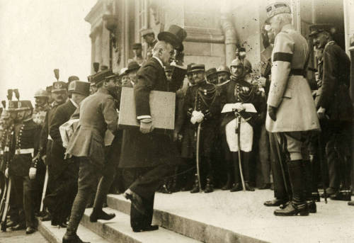 collectivehistory:  French official from the Ministry of Foreign Affairs holds a box with a peace treaty at the entrance to the Palace of Versailles,1919 (via) 