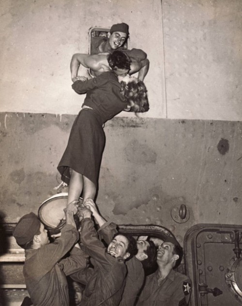 Actress Marlene Dietrich is hoisted up to kiss a GI as he arrives home from World War II