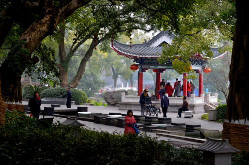 Guilin had many parks where people could stroll under large over hanging trees. A small pagoda sat b