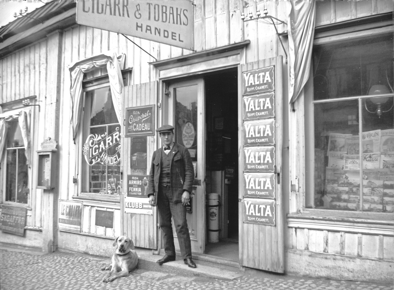 Man and dog outside a tobacco store. Sweden.