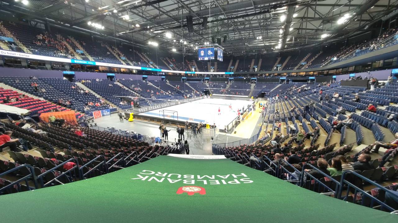 Blick auf eine große Halle mit Oberrängen für über 10.000 Menschen. Auf dem Feld wärmen sich Spieler auf.