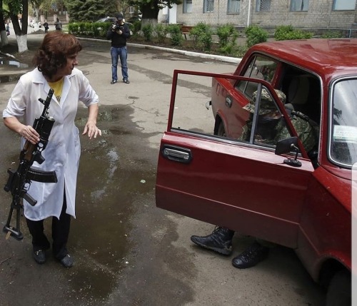  Donbass, 2014 - a nurse temporarily holds an AK-74 as she assists a wounded pro-Russian militant ou