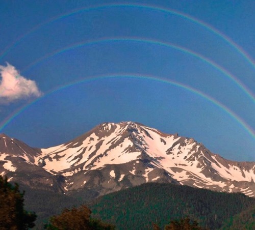cookpot:[id: Photo of a mountain covered in snow, with not one but three rainbows in the clear sky a