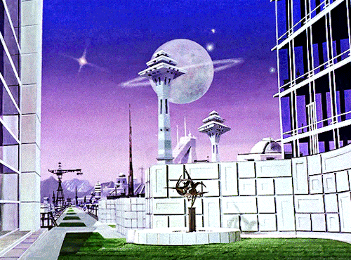GIF 1: scenic view of a public square and cityscape. the square is a patch of grass surrounded by a white sidewalk. in the center of it is a futuristic looking statue of sorts. on both hand sides of the frame is a tall building with large windows. on the left side the sidewalk disappears into the distance toward a mountainous landscape. on the edge of the square is a white wall and behind it in the distance are two towers. a full moon and several stars hang in the sky. the sky is coloured a beautiful blue to purple gradient.