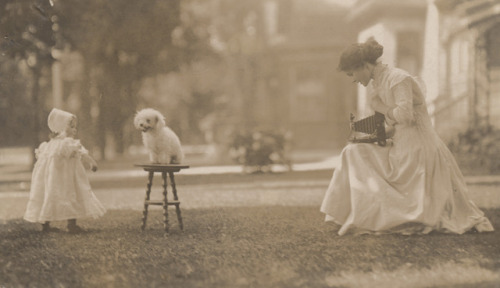 vintageeveryday:Young woman photographing her daughter and dog, circa 1900.