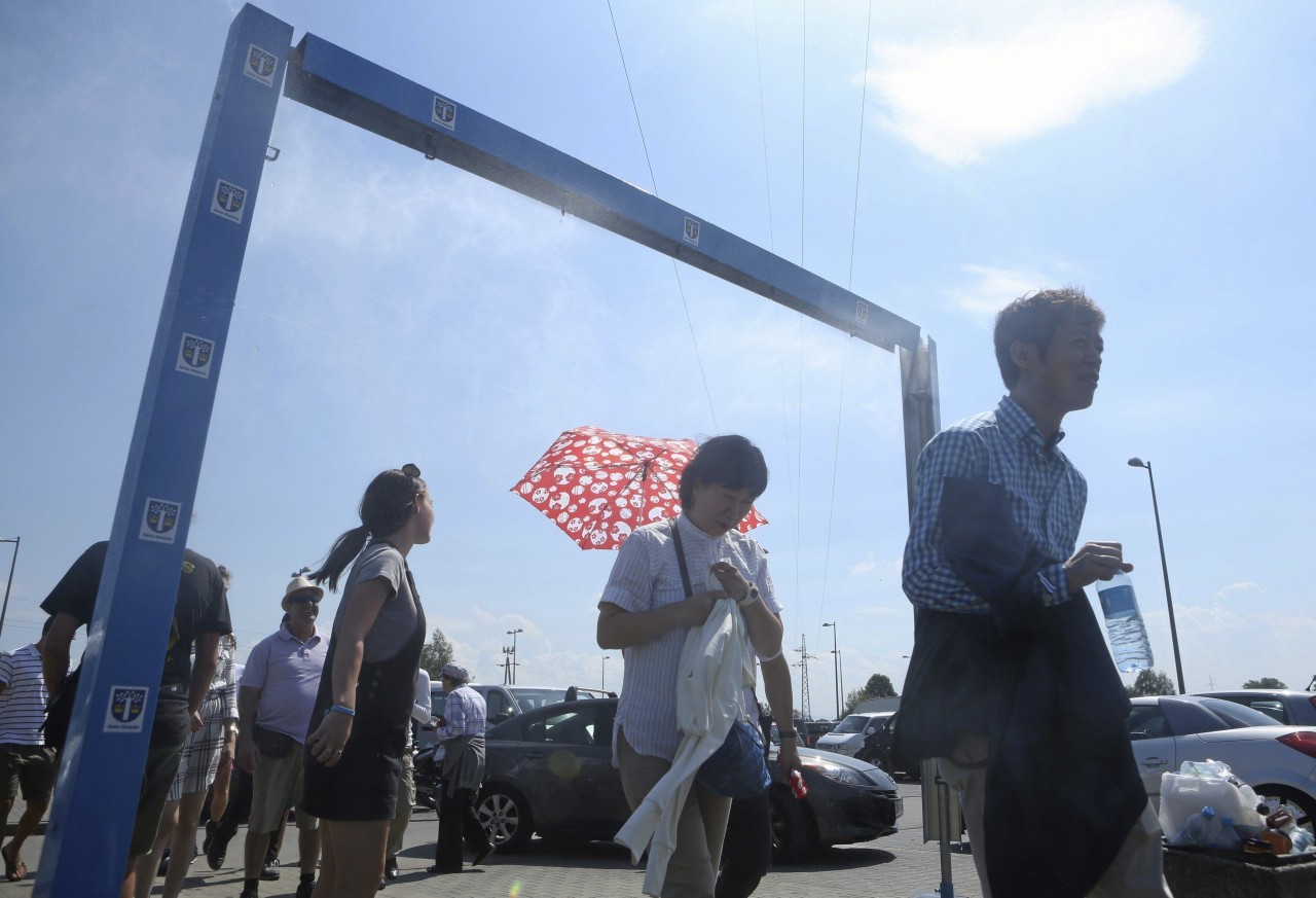 AUSCHWITZ. Los turistas se refrescan bajo los aspersores de agua en el estacionamiento del Museo Auschwitz-Birkenau en Oswiecim, Polonia. Los aspersores destinados a refrescar a las personas que visitan el museo durante el sofocante calor, han...