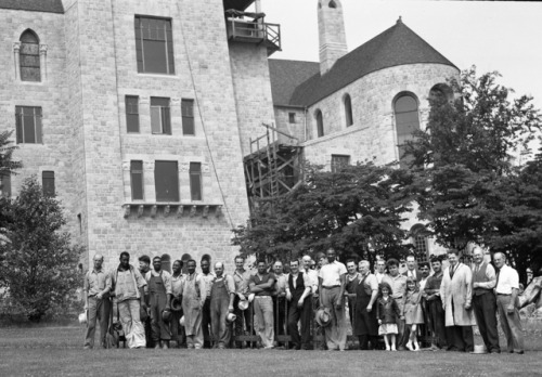 Craftsmen and workmen pose with a section of Monel metal railing before it is hoisted up to the obse