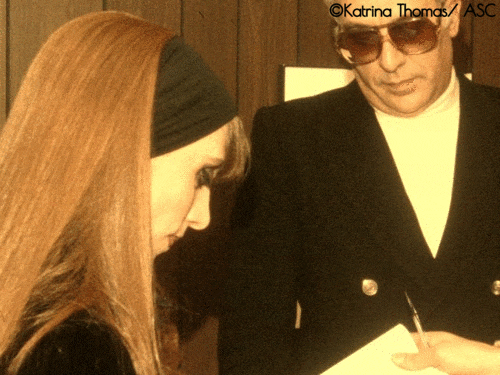 Fairuz escorted by her own brother Joseph Haddad in 1981 during her Legend and Legacy US tour, while autographing for a lucky fan a poster-size picture of her, taken by Dencho Valserra.
