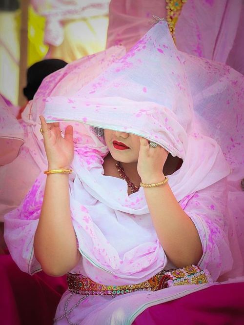 Beautiful veiled woman protecting themselves from the colored powders, Holi Festival at Radha Govind