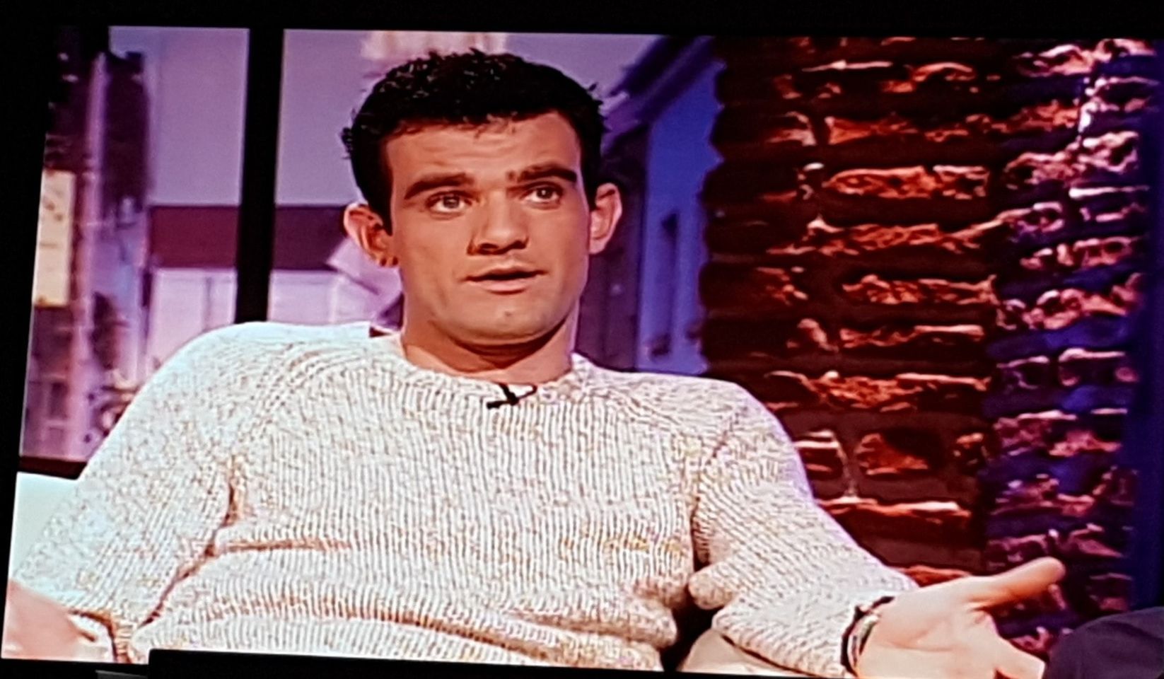 Camera shot of a scene of Stefán Karl on Gnarrenburg speaking about Rainbow Children