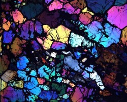 smithsonian:  This is a 30-micron thick slice of ureilite meteorite under a microscope with polarized light. The colors reveled show different levels of magnesium and iron in olivine and pyroxene crystals. The shattered appearance reflects how the former