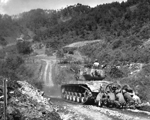 Marines take cover behind an M26 Pershing while it fires on Communist troops in the Hongcheon area. 