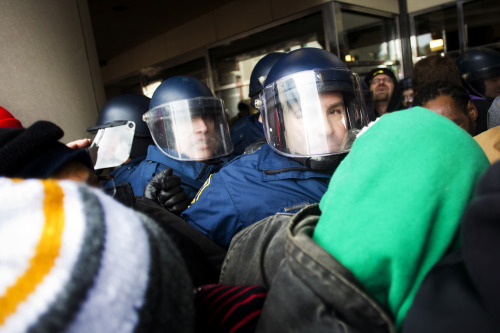 Michigan State Police officers struggle to push back protestors as they crowd the George W. Romney B
