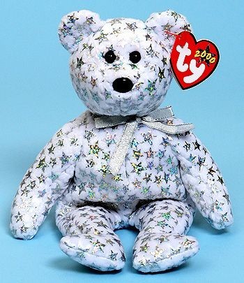 a white bear plush with a silver ribbon tied in a bow around it's neck. There are shiny, iridescent stars covering the fabric of the bear.